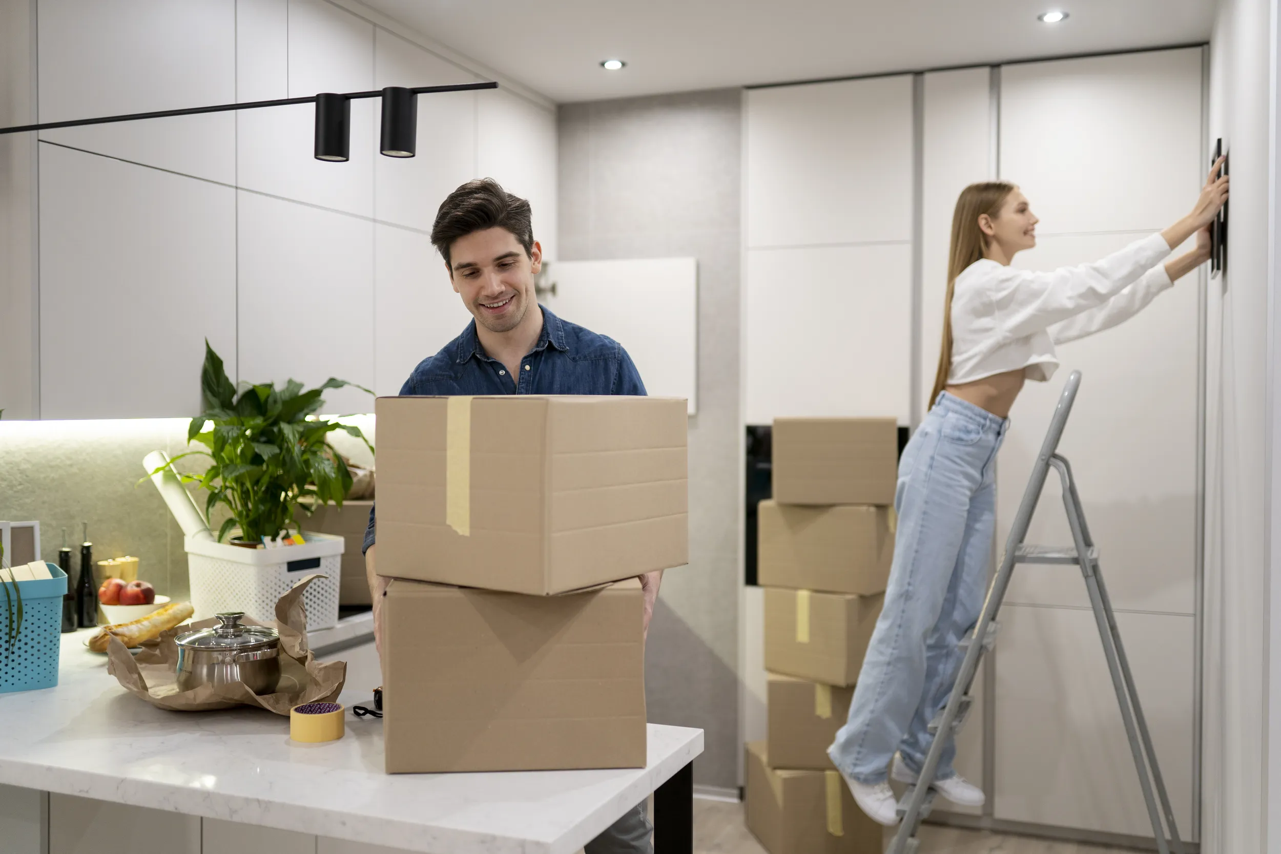 woman hanging frame wall while her boyfriend is handling